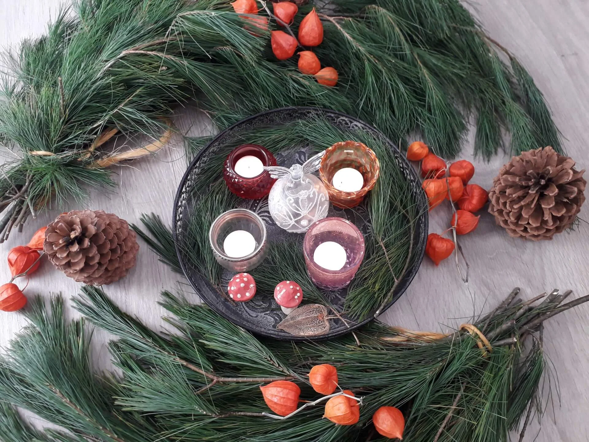 Dennentakken met waxinelichtjes en oranje lampionnetjes